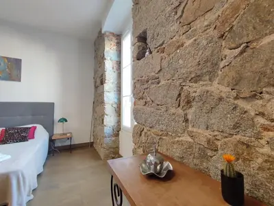 a room with a stone wall and a bed and a table at Studio de 25m2 - Extra centre - À 5 min à pied des plages - Commerces et restaurants sur place - Clim - Wifi - EXCEPTIONNEL in Ajaccio