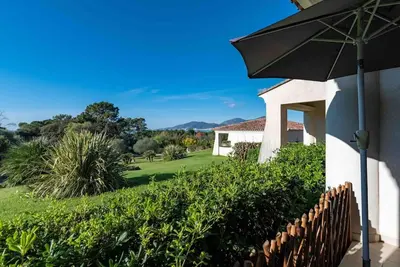 a house with an umbrella and a yard at Bella Vista , à Porticcio, joli appartement vue mer in Grosseto-Prugna