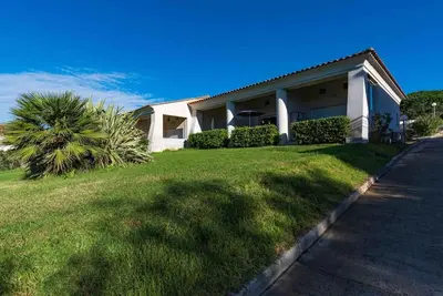 a house with a palm tree in front of a yard at Bella Vista , à Porticcio, joli appartement vue mer in Grosseto-Prugna