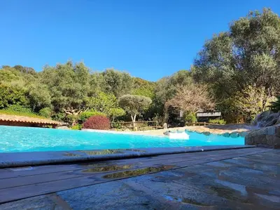 a swimming pool with blue water and trees in the background at Casa Marcelli 5 in Porto-Vecchio