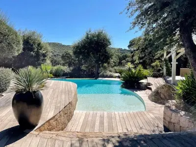 a swimming pool in a garden with a wooden deck at Villa Valentine by Intendance Excellency in Porto-Vecchio