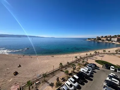 a beach with a bunch of cars parked next to the water at Le Face à La Mer in Ajaccio