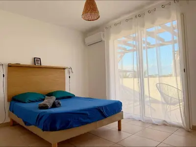 a bedroom with a bed and a large window at Corse - Bord de mer, Appartement neuf avec Piscine Chauffée in Linguizzetta