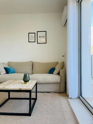 a living room with a couch and a table at Corse - Bord de mer, Appartement neuf avec Piscine Chauffée in Linguizzetta