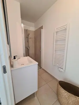 a white bathroom with a sink and a shower at Corse - Bord de mer, Appartement neuf avec Piscine Chauffée in Linguizzetta