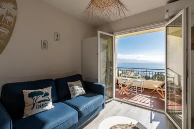 a living room with a blue couch and a view of the ocean at A Piaghja, refuge romantique face à la mer in Ajaccio