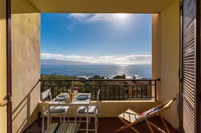 a balcony with a table and chairs and a view of the ocean at A Piaghja, refuge romantique face à la mer in Ajaccio