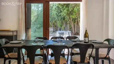a dining room table with a bottle of wine and chairs at Villa Colombo in Bonifacio