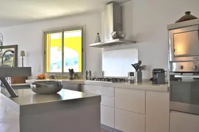 a large kitchen with white cabinets and a sink at Villa Roccu in Borgo