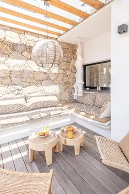 a living room with two tables and a stone wall at Villa Bambou 12 pers piscine chauffée 10 minutes à pieds plage in Sainte-Lucie de Porto-Vecchio