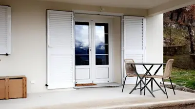 a patio with a glass door and a table and chair at Studio Venaco Centre Corse in Venaco