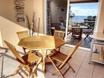 a wooden table and chairs in a kitchen with a balcony at F2 vue mer dans résidence avec piscine in Ajaccio