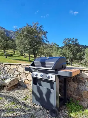 a grill sitting next to a stone wall at Maison en pierre corse avec vue entre mer et montagne in Moltifao