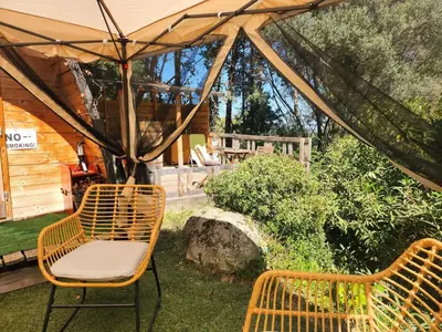 a wooden deck with chairs and a table and a barrel at Cabana Exotique Piscine et Jacuzzi in Porto-Vecchio
