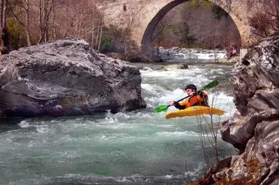 a man in a kayak in a river with a bridge at Charmant petit logement à 3 kms de la plage in Belgodère
