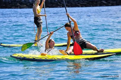 a group of people on a paddle board in the water at Charmant petit logement à 3 kms de la plage in Belgodère