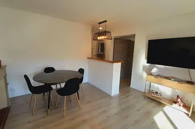 a living room with a table and chairs and a flat screen tv at Appartement lumineux et central in Propriano