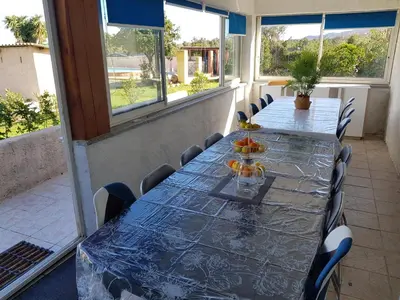 a long table with chairs in a room with windows at GIORGHA VILLA Piscine chauffée 15 pers avec piscine vue mer montagne 1km mer in Solaro