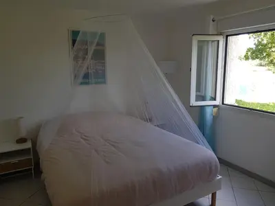a bed with a mosquito net in a room with a window at GIORGHA VILLA Piscine chauffée 15 pers avec piscine vue mer montagne 1km mer in Solaro