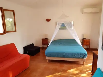 a bedroom with a bed with a mosquito net at LA MARINE Piscine chauffée villa avec piscine 5 mn à pied de la mer in Solaro