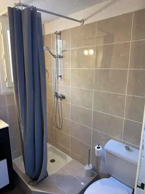 a bathroom with a blue shower curtain and a toilet at Maison D Santa Giulia in Porto-Vecchio