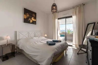 a bedroom with a large white bed and a window at Ajaccio, les Cyclades, magnifique appartement vue mer in Ajaccio