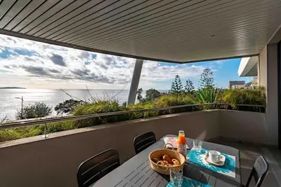a table on a balcony with a view of the water at Ajaccio, les Cyclades, magnifique appartement vue mer in Ajaccio