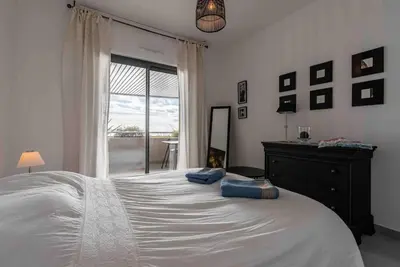 a bedroom with a large white bed and a window at Ajaccio, les Cyclades, magnifique appartement vue mer in Ajaccio