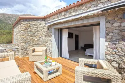 a patio of a house with a stone wall at Maison en pierre Corse avec vue proche des Gorges de l'Asco entre mer montagne et piscine in Moltifao