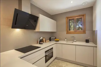 a kitchen with white cabinets and a flat screen tv at Maison en pierre Corse avec vue proche des Gorges de l'Asco entre mer montagne et piscine in Moltifao