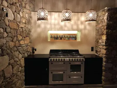 a kitchen with a stove and a counter with lights at Maison en pierre Corse avec vue proche des Gorges de l'Asco entre mer montagne et piscine in Moltifao