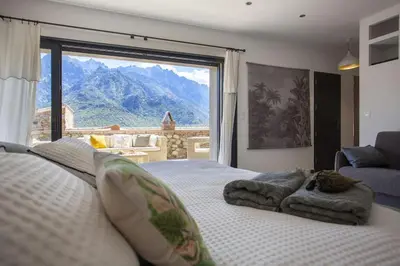 a bedroom with a bed with a view of the mountains at Maison en pierre Corse avec vue proche des Gorges de l'Asco entre mer montagne et piscine in Moltifao