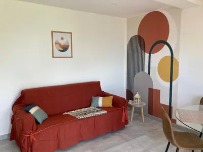 a living room with a red couch and a table at Chez Jean Claude la villa des amis in Olmeto