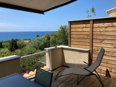 a balcony with two chairs and a view of the ocean at Chez Jean Claude la villa des amis in Olmeto