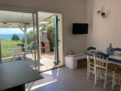a living room with a table and a sliding glass door at Chez Jean Claude la villa des amis in Olmeto