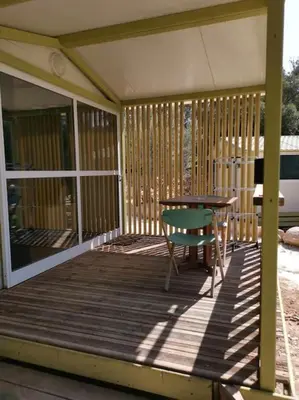 a wooden deck with a table and a chair at Grande Chambre tout confort 3 in Bonifacio