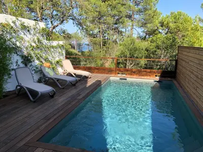 a swimming pool on a deck with two chairs next to it at Apartment Les Jardins d'Ève-F2 by Interhome in Favone