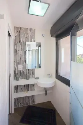 a bathroom with a sink and a mirror and a window at Le SAN PETRONE-TOUR EN PIERRE EN CENTRE CORSE ENTRE MER ET MONTAGNE in Moltifao