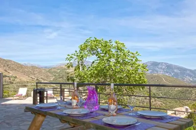 a wooden table with plates and wine bottles on it at Le SAN PETRONE-TOUR EN PIERRE EN CENTRE CORSE ENTRE MER ET MONTAGNE in Moltifao