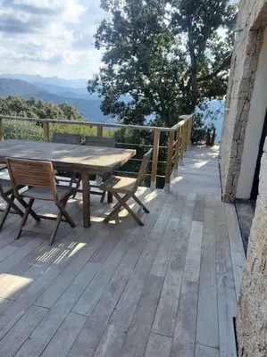 a wooden deck with a wooden table and benches at Meublé de tourisme avec terrasse vue montagne in Grossa