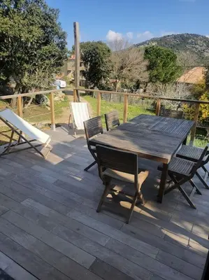 a wooden table and chairs on a wooden deck at Meublé de tourisme avec terrasse vue montagne in Grossa