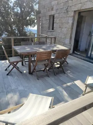 a wooden table and chairs on a deck at Meublé de tourisme avec terrasse vue montagne in Grossa