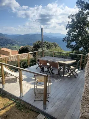 a wooden deck with a table and chairs on it at Meublé de tourisme avec terrasse vue montagne in Grossa