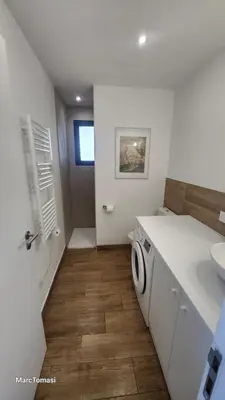 a bathroom with a washer and dryer in a room at Meublé de tourisme avec terrasse vue montagne in Grossa