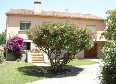 a tree in front of a house with pink flowers at Casa Rossa Solenzara in Sari Solenzara