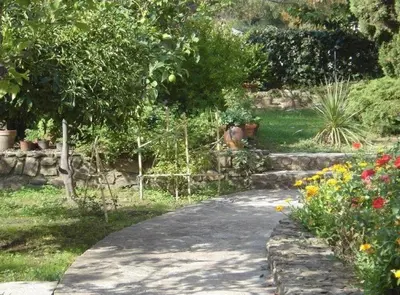 a walkway in a garden with flowers and trees at Casa Rossa Solenzara in Sari Solenzara