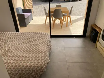 a bedroom with a bed and a table and chairs at T1 traversant, plain pied entre mer et montagne in Cuttoli-Corticchiato