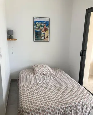 a bed in a bedroom with a picture on the wall at T1 traversant, plain pied entre mer et montagne in Cuttoli-Corticchiato