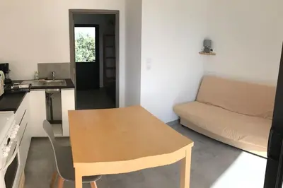 a small kitchen with a table and a couch at T1 traversant, plain pied entre mer et montagne in Cuttoli-Corticchiato