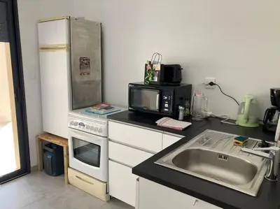 a kitchen with a sink and a refrigerator and a microwave at T1 traversant, plain pied entre mer et montagne in Cuttoli-Corticchiato